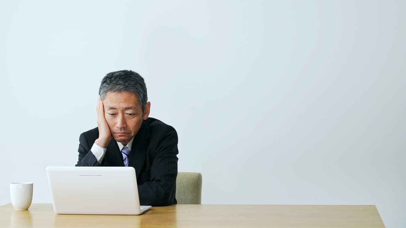 パソコンの前で頭を抱えるビジネスパーソン